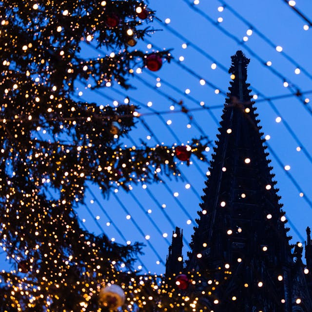 Spitzen des Kölner Doms sind hinter der Beleuchtung des Weihnachtsmarkts auf dem Roncalliplatz zu sehen