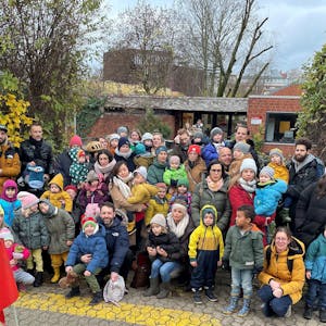 Eltern und Kinder stehen vor der städtischen Kindertagesstätte Weyertal.