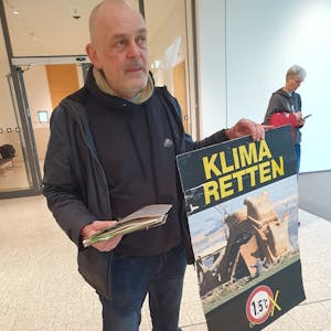 Winfried Bernhardt, Klimaaktivist, steht mit einem Plakat mit der Aufschrift «Klima retten» im Foyer des Gerichts. Wegen einer Attacke mit Kartoffelbrei im NRW-Landtag musste er sich vor Gericht verantworten. Die Staatsanwaltschaft warf ihm Sachbeschädigung vor.&nbsp;