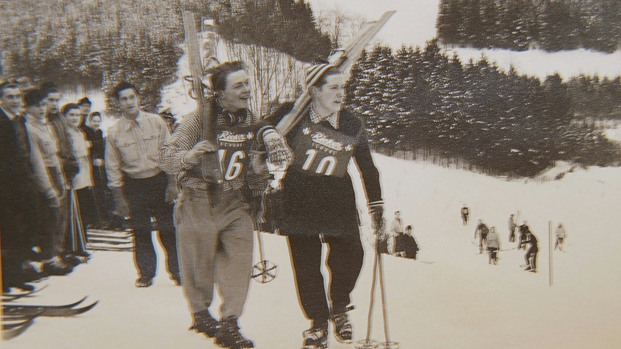 Männer tragen ihre Skier den Berg hinauf.