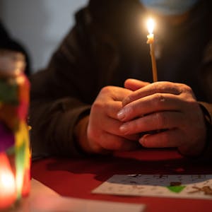 Eine Person umschließt mit zwei Händen eine kleine Kerze.