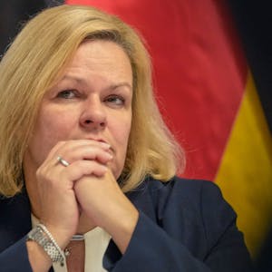 Nancy Faeser (SPD), Bundesministerin für Inneres und Heimat, mit gefalteten Händen, hinter ihr die Deutschlandfahne.