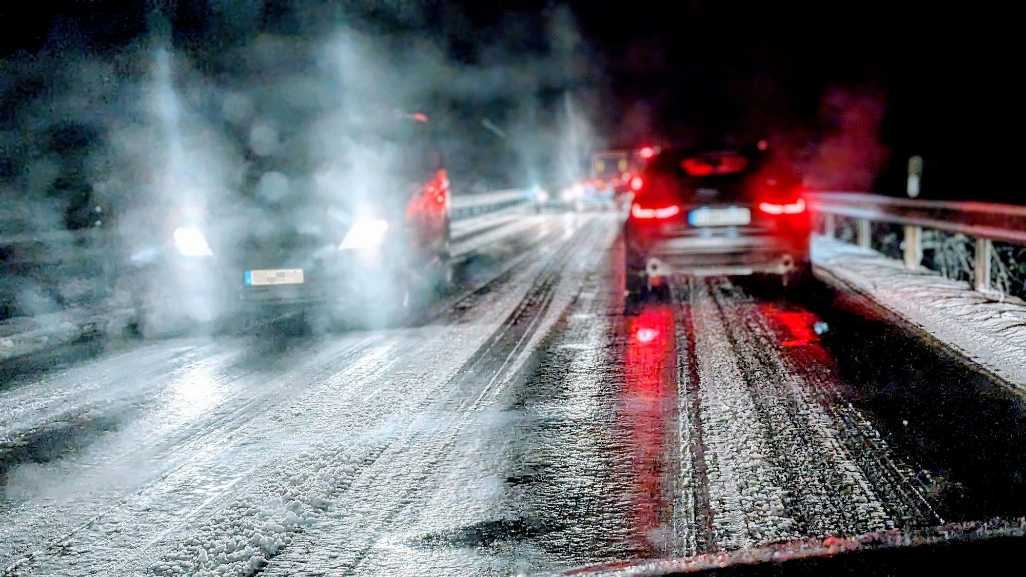 Auf einer Landstraße im Kreis Euskirchen fahren mehrere Autos bei Nacht über eine vereiste Straße. Am Straßenrand liegt Schnee. (Archivbild)