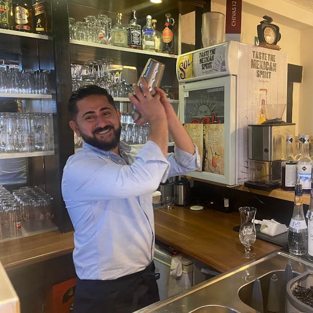 Ein Mann steht hinter einer Bar und mixt einen Cocktail