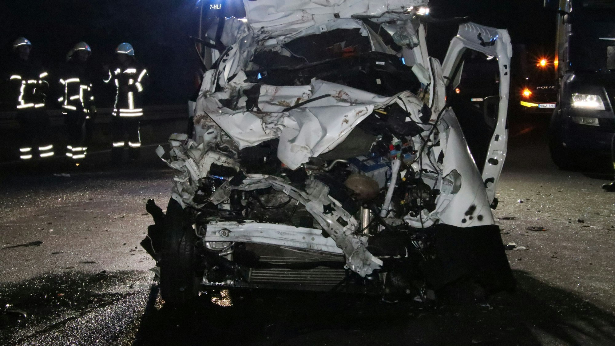 Foto eines völlig zerstörten weißen Kleinlasters, der im Dunkeln auf der Autobahn steht.