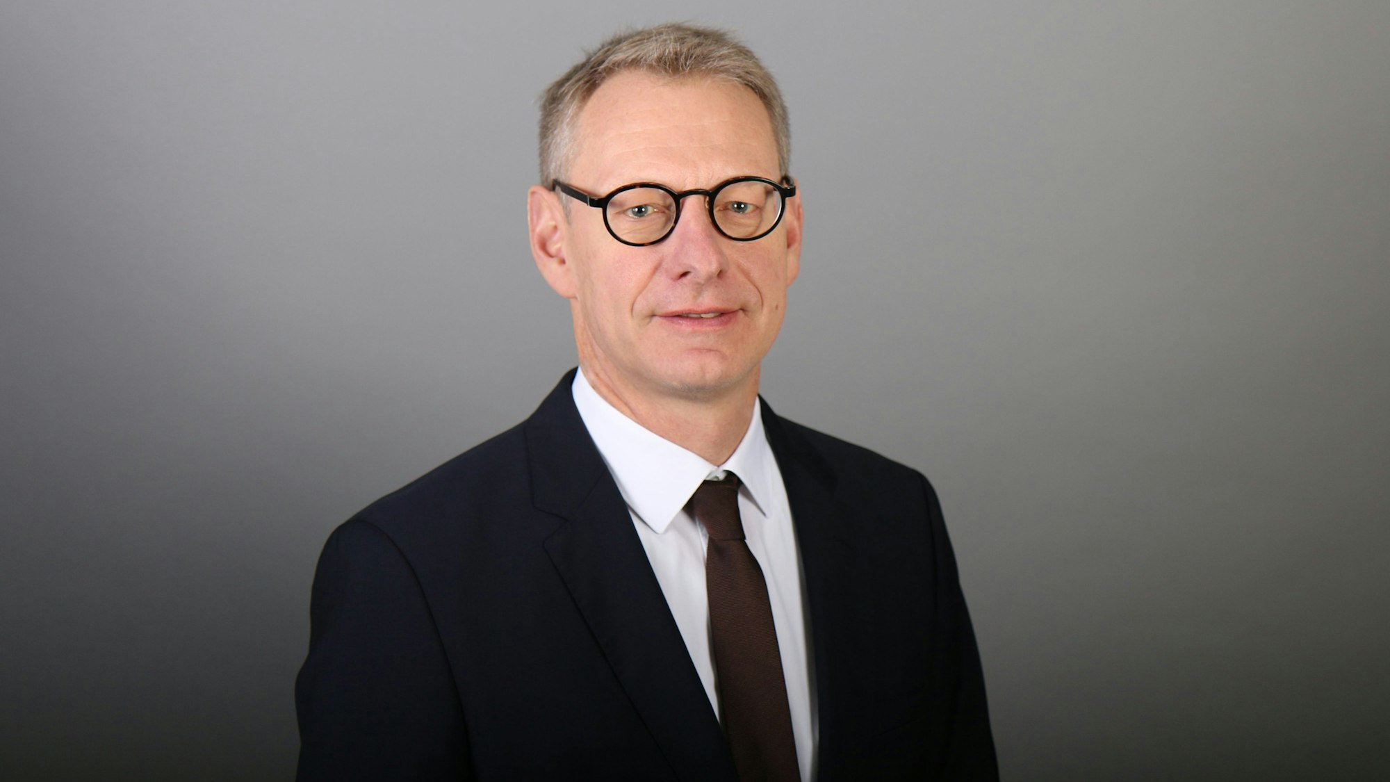Christoph Breuer, Professor der Deutschen Sporthochschule Köln (DSHS), ist im Porträt zu sehen. Er trägt einen schwarzen Anzug und dunkle Krawatte.