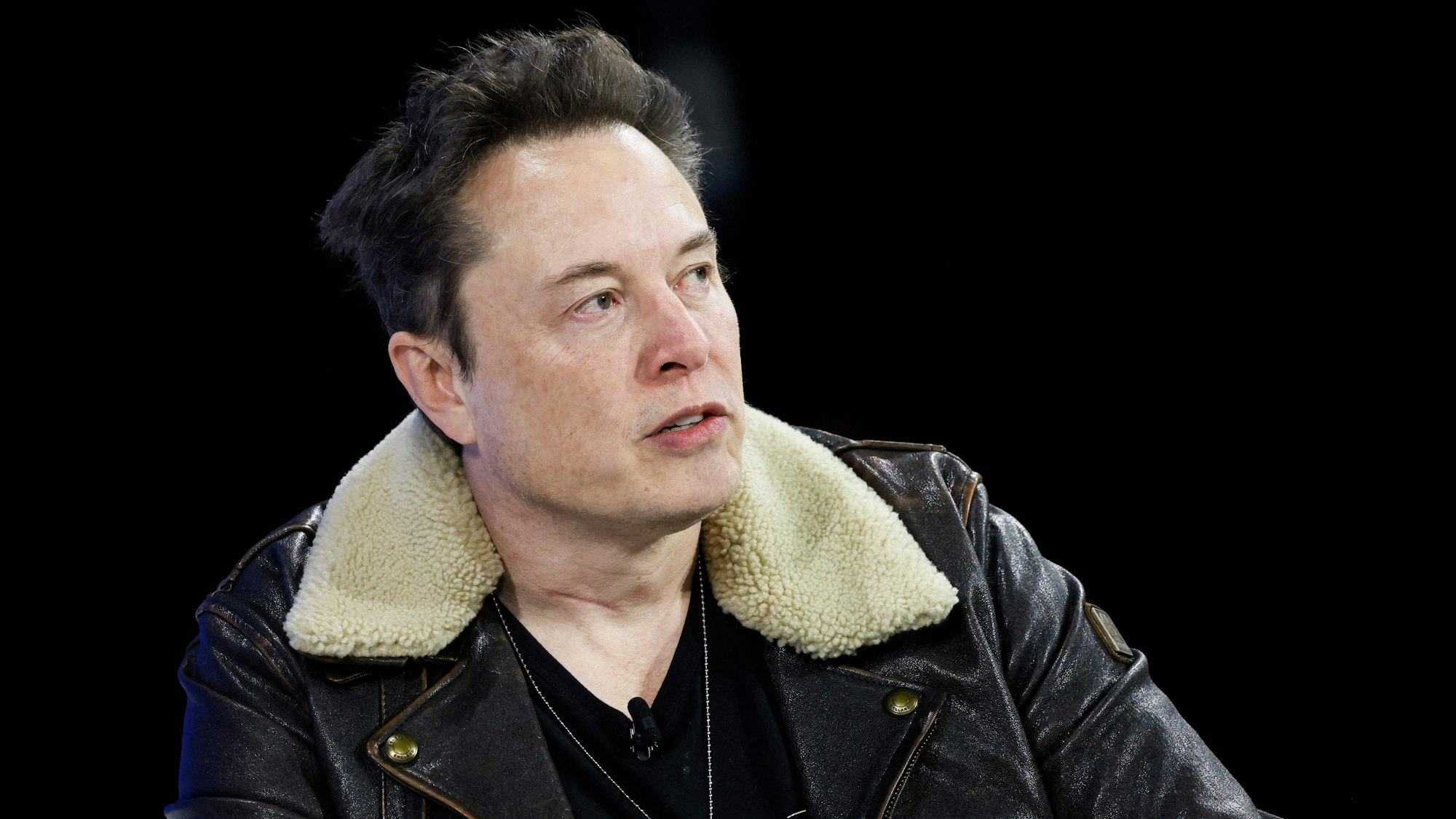 Elon Musk trägt eine schwarze Lederjacke und ein schwarzes T-Shirt.
