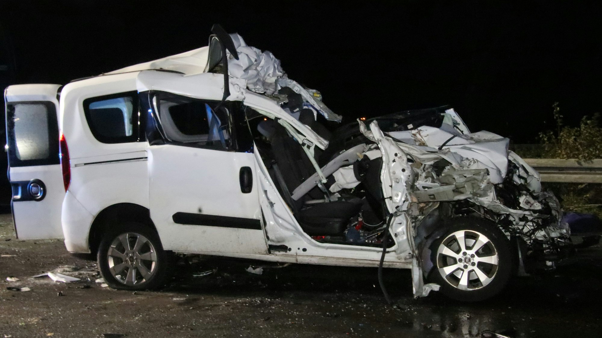 Seitliche Aufnahme eines weißen Unfallautos, das an der Front komplett zerstört ist.