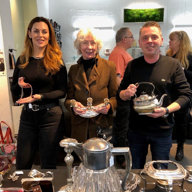 Salon-Mitarbeiterin Tamara Ergiden, Hedwig Neven DuMont und Ralph Schwalbach halten bei der Eröffnung der Benefiz-Börse„ Schmuckstücke im Salon“ kostbares Silber in der Hand.