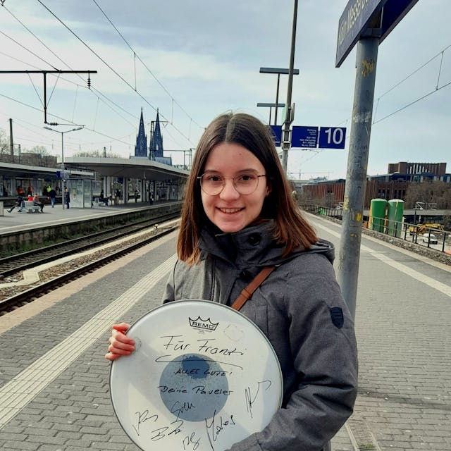 Die Teenagerin Franziska steht mit einer Trophäe ihrer Kölner Lieblingsband am Bahngleis des Deutzer Bahnhofs.