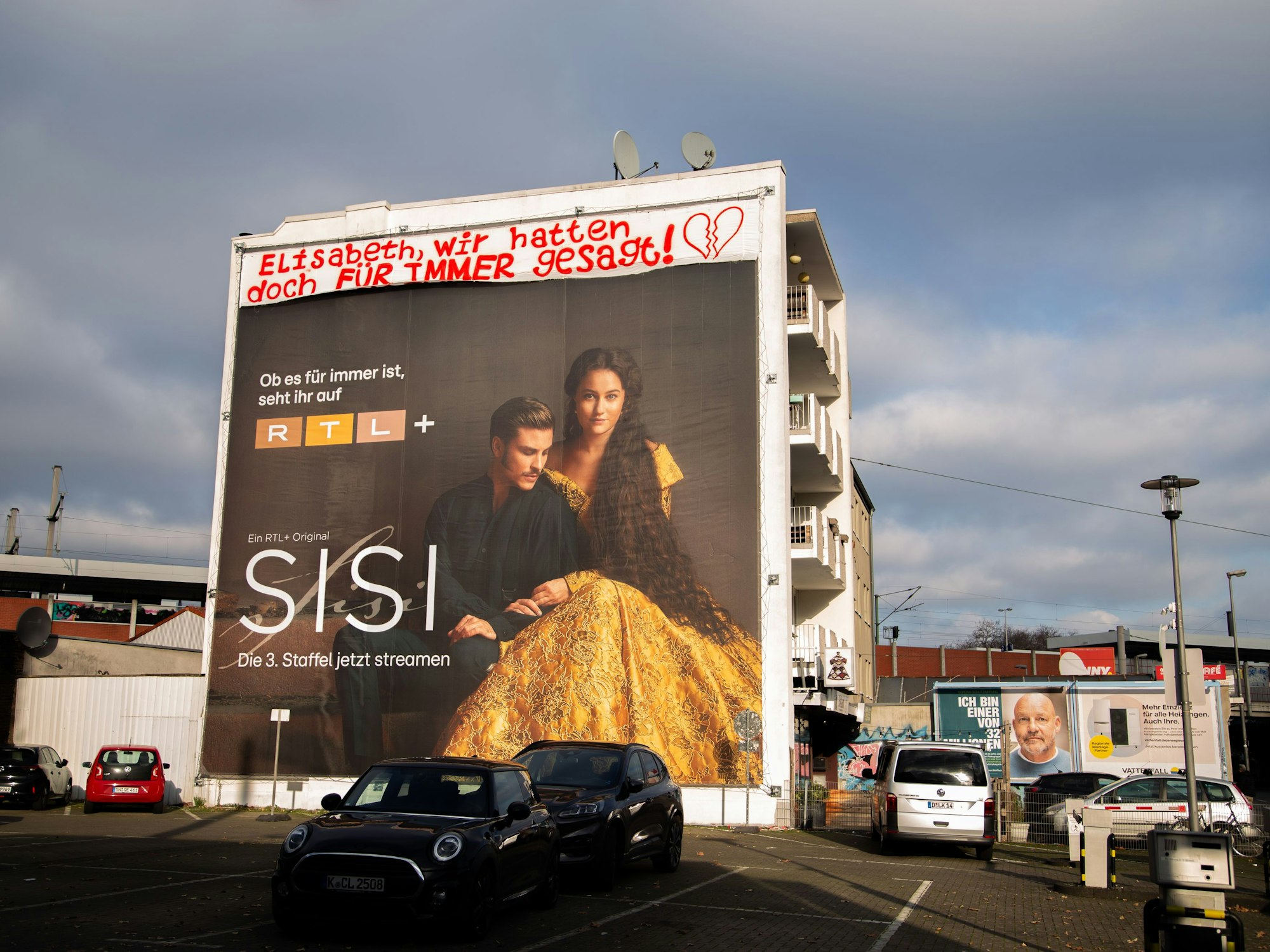 Ein Sisi-Werbeplakat hängt unter der Liebesbotschaft an einer Kölner Hauswand.