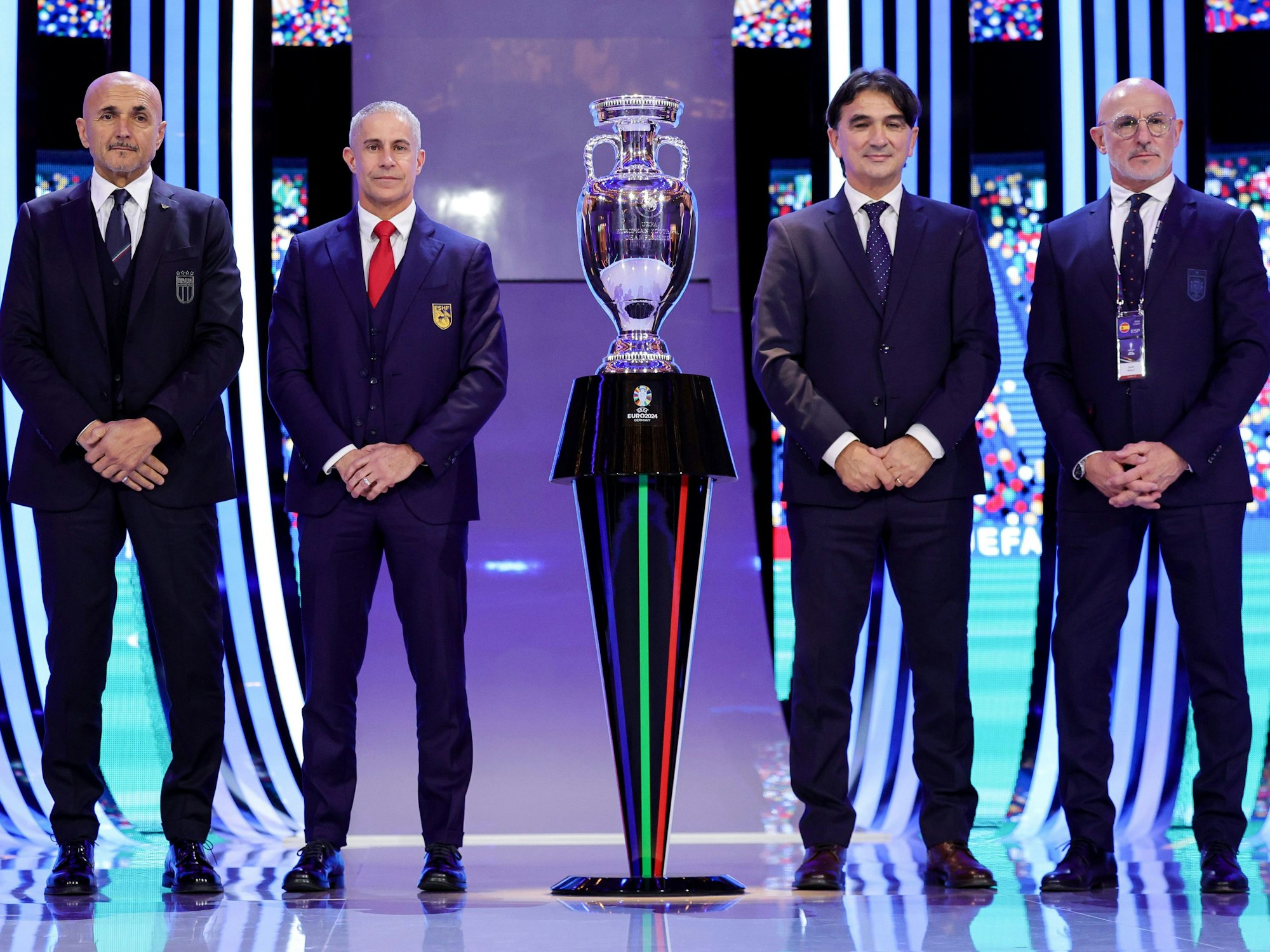 Die Nationaltrainer (v.l.) Luciano Spalletti von Italien, Sylvinho von Albanien, Zlatko Dalic von Kroatien sowie Luis de la Fuente von Spanien stehen neben der EM-Trophäe.