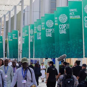 Participants walk past banners at the COP28 United Nations climate summit in Dubai on December 3, 2023. (Photo by Giuseppe CACACE / AFP)