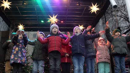 Kinder stehen auf einer weihnachtlich geschmückten Bühne.