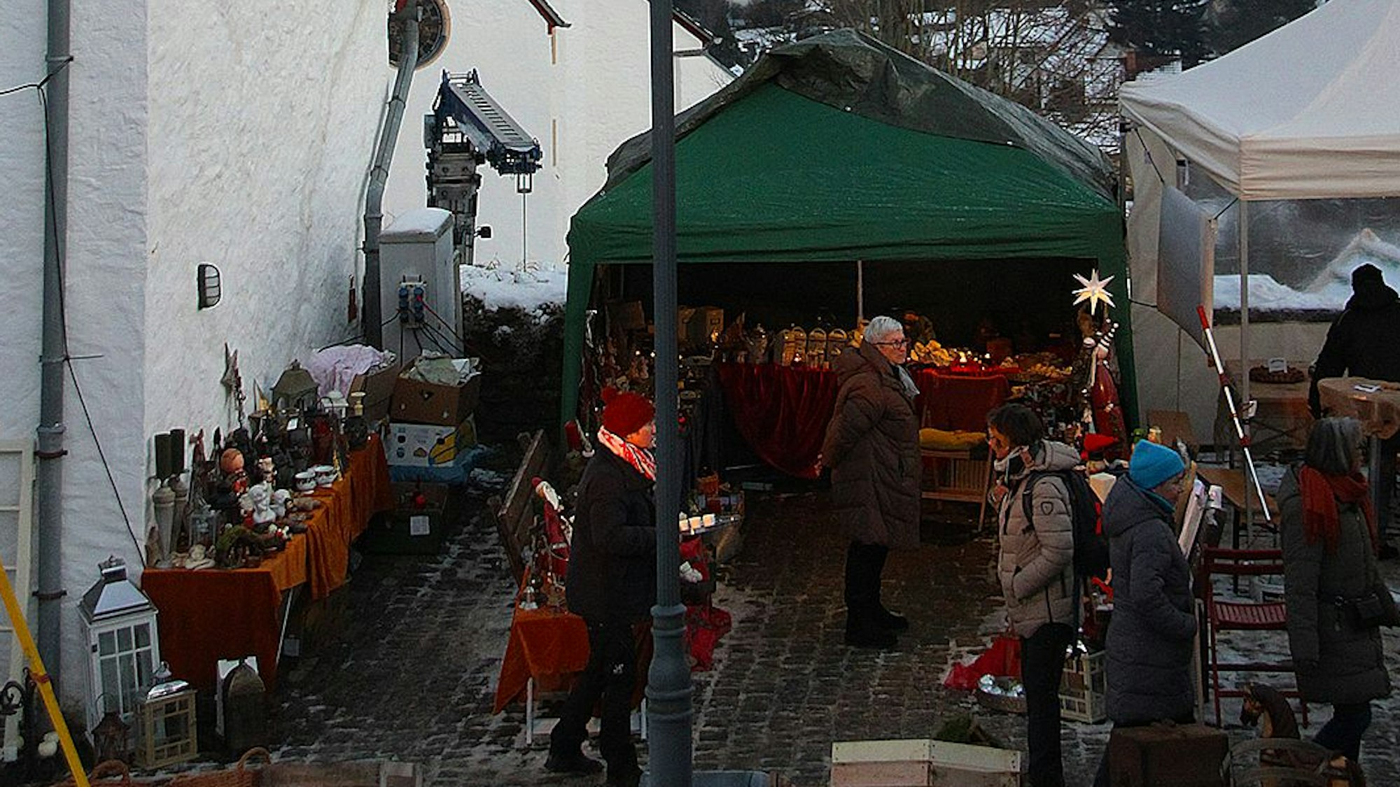 Das Bild zeigt im Vordergrund einen Teil es Weihnachtsmarkts, im Hintergrund ist die verschneite Landschaft zu sehen.