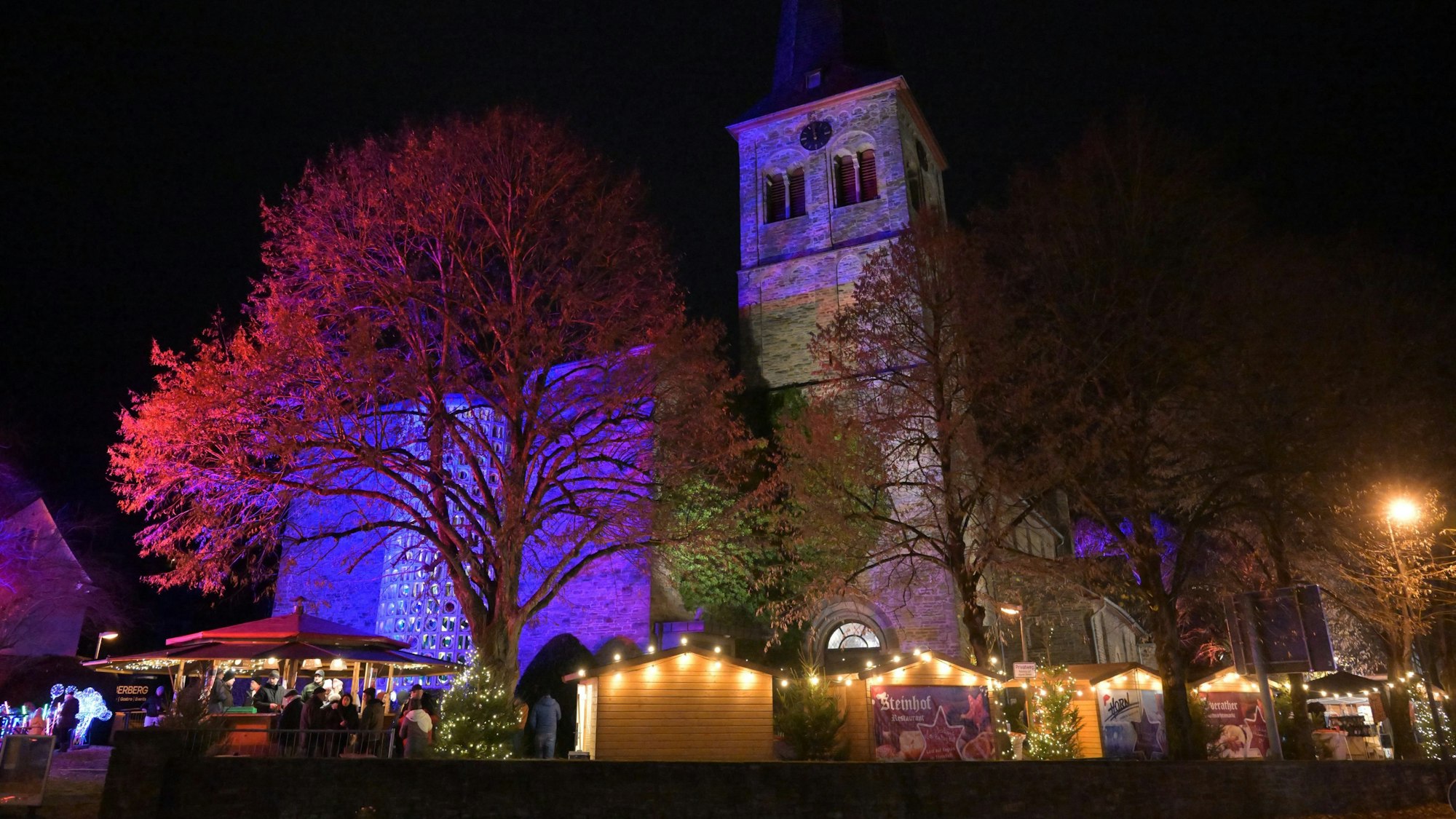 Weihnachtsmarkt an St. Walburga Overath. Die Kirche ist illuminiert.