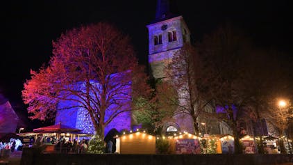 Weihnachtsmarkt an St. Walburga Overath. Die Kirche ist illuminiert.