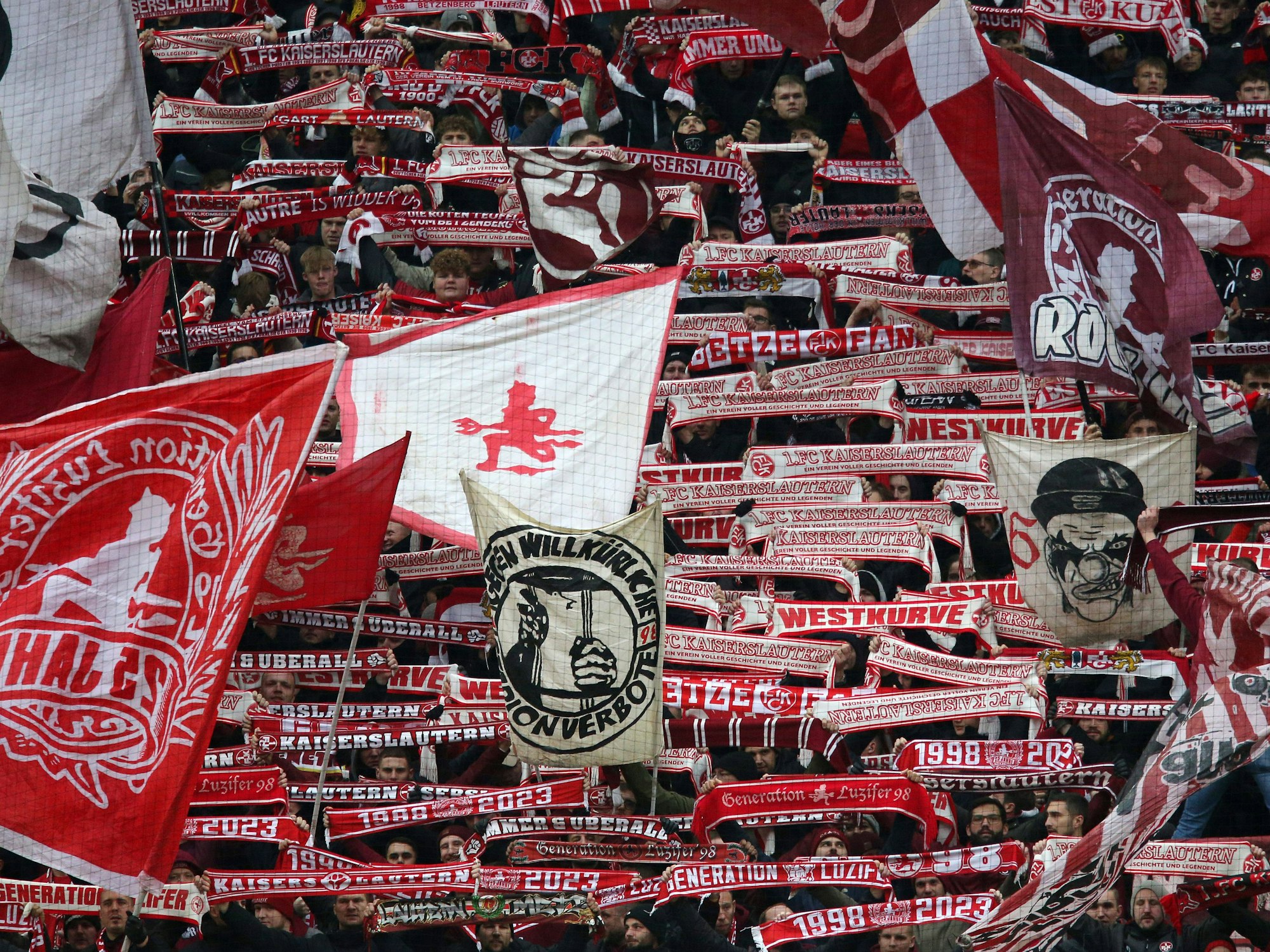 Fans des 1. FC Kaiserslautern halten auf der Tribüne ihre Schals in die Luft.