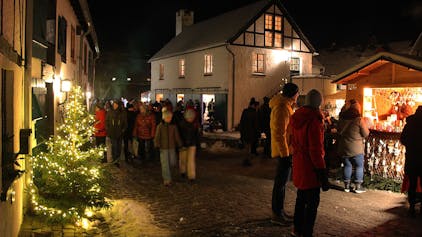 Der Burgbering in Kronenburg ist weihnachtlich geschmückt, zahlreiche Menschen schlendern an Buden und Häusern vorbei