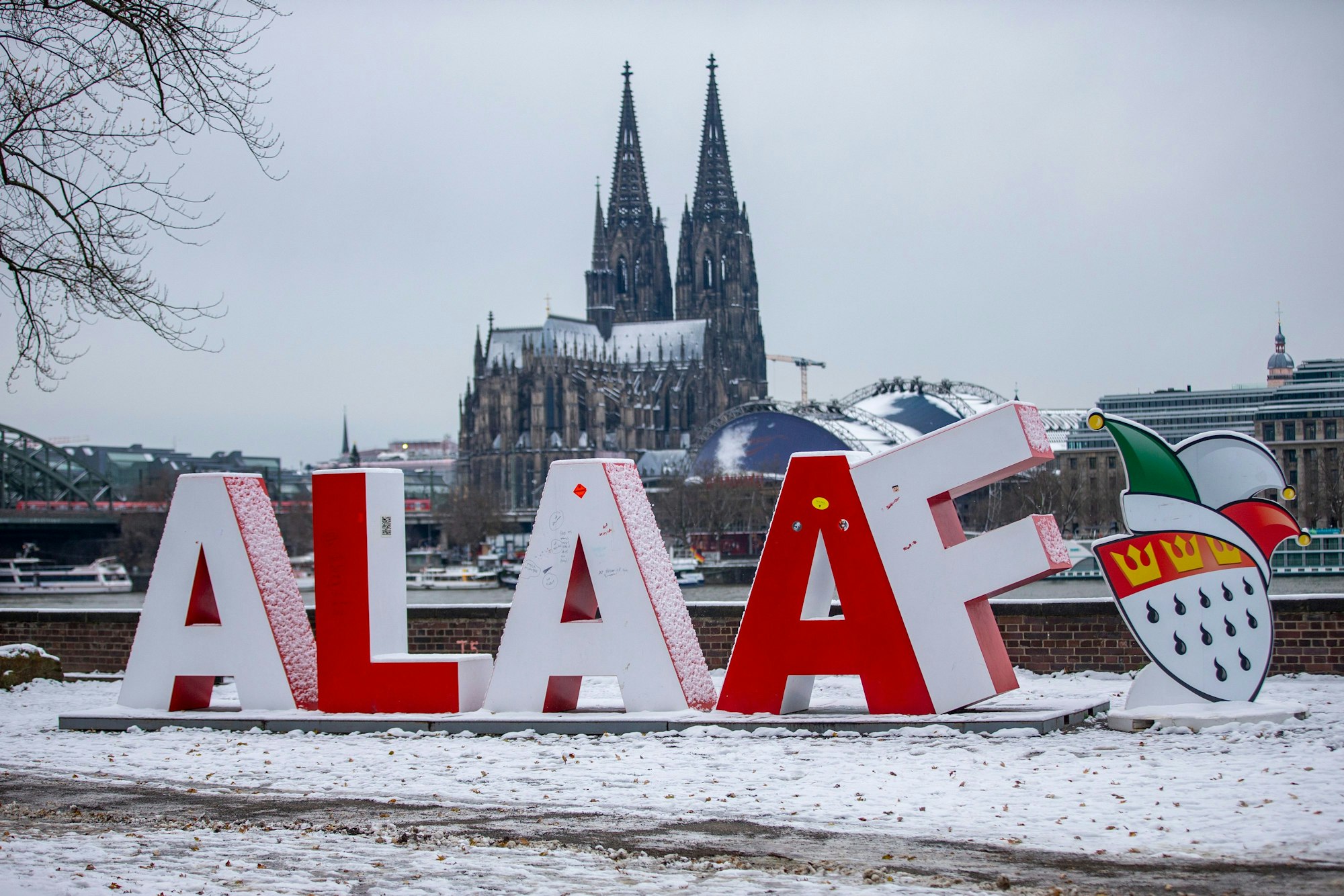 Der eingeschneite Schriftzug Alaaf, im Hintergrund der Rhein und der Kölner Dom. Auch am Montagmorgen prägte der Schnee noch das Stadtbild.