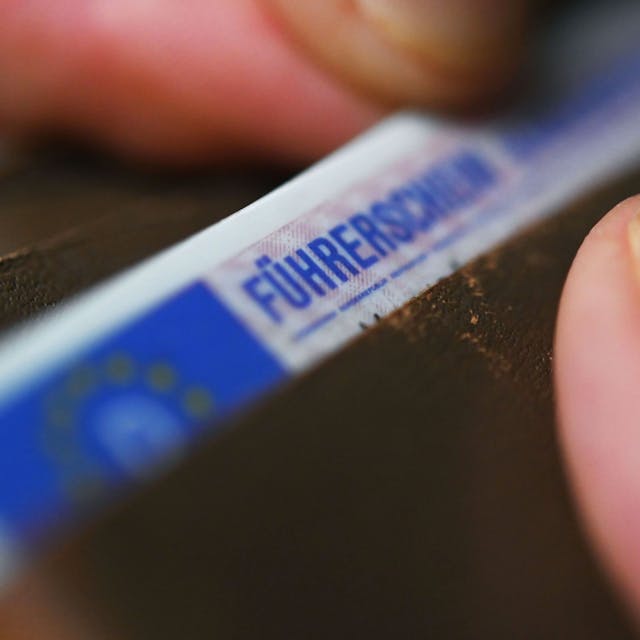 Eine Frau nimmt einen Führerschein im EU-Scheckkartenformat aus ihrem Geldbeutel.