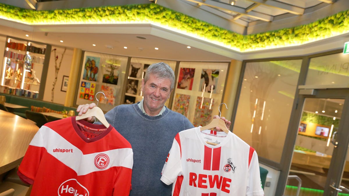 Friedhelm Funkel hält zwei Trikots von Fortuna Düsseldorf und dem 1. FC Köln in die Kamera.&nbsp;