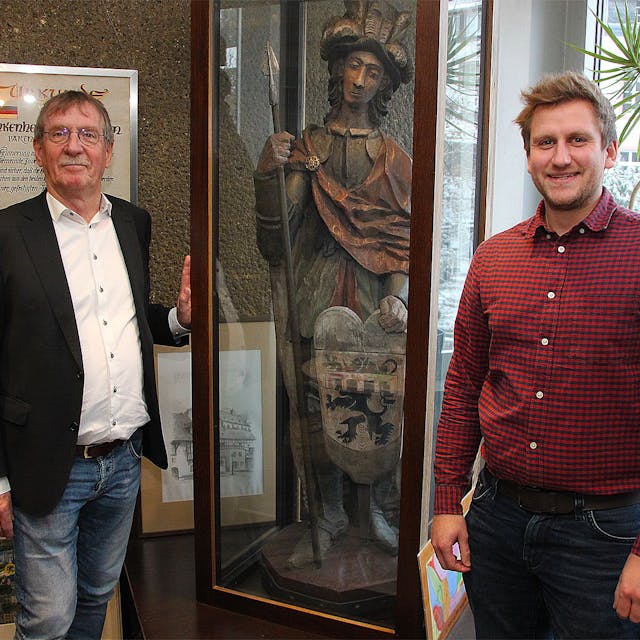 Erwin Nelles (links) und Robin Poensgen stehen an der Vitrine im Blankenheimer Rathaus, in der die Figur des heiligen Nepomuk mit dem Wappen aufbewahrt wird.