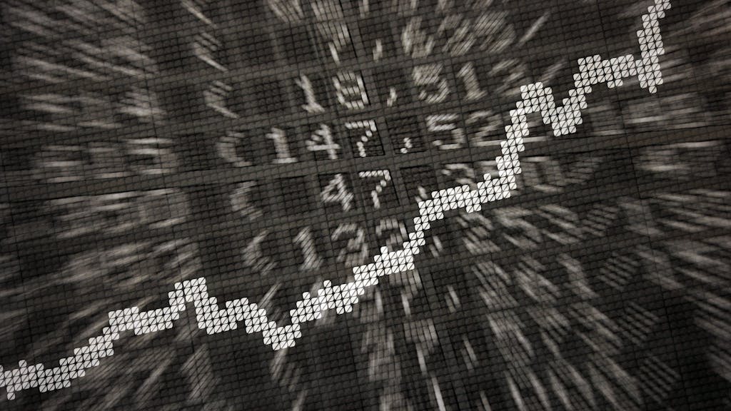 Eine Anzeige in der Börse zeigt die Dax-Kurve und verschiedene Börsenkurse.
