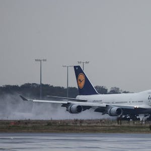Eine Boeing 747 der deutschen Fluggesellschaft Lufthansa im Landeanflug bei einem Unwetter. Der Regen auf der Landebahn wird aufgewirbelt. (Symbolbild)