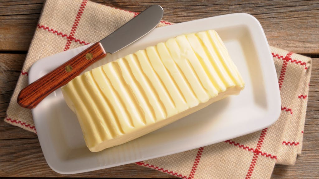 Auf dem Foto sieht man ein großes Stück Butter auf einem Teller liegen.