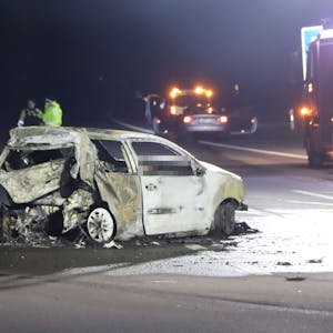 Einsatzkräfte stehen in der Nacht auf der Autobahn in der Nähe eines ausgebrannten VW-Polos. Die Autobahn, auf der der Wagen steht, ist komplett gesperrt.