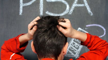 Ein Schüler rauft sich in vor dem mit Kreide an eine Schultafel geschriebenen Wort PISA die Haare. Das Ergebnis des Pisa-Test fiel schlecht aus