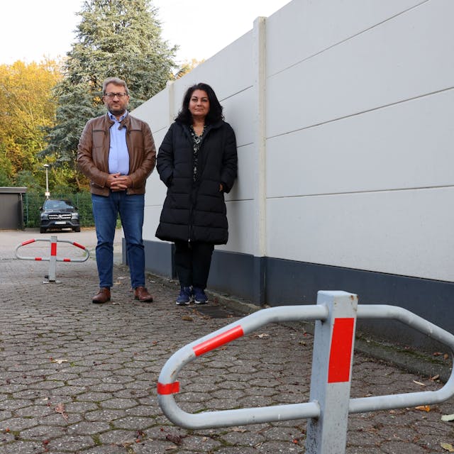 Latif Bekiri und Perwin Sakar stehen vor der Mauer vor ihrem Grundstück. Im Vordergrund ein Poller.