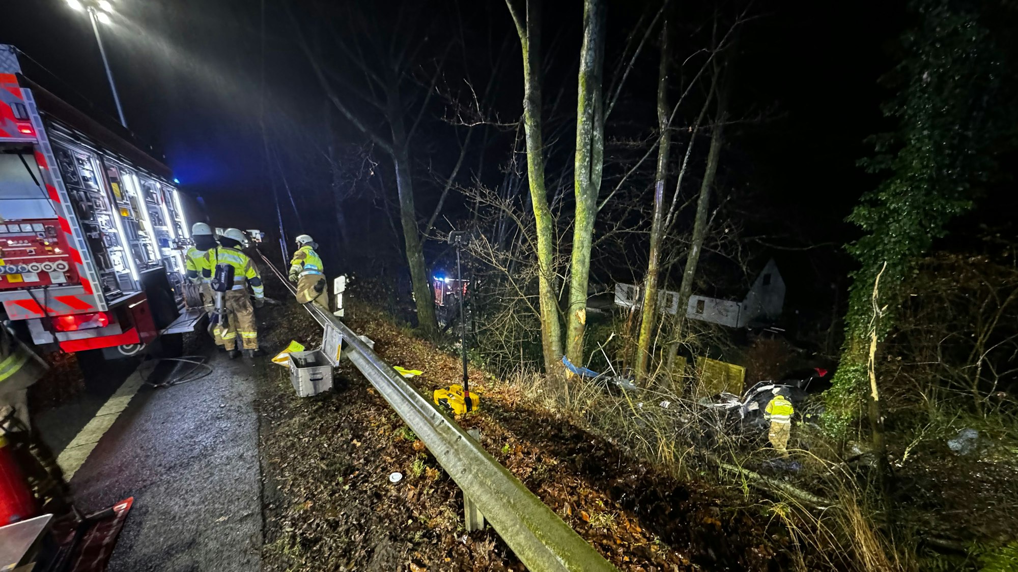 Feuerwehr in Bergisch Gladbach im Einsatz an einer Böschung, wo ein Auto in die Tiefe gestürzt ist.