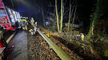 Feuerwehr in Bergisch Gladbach im Einsatz an einer Böschung, wo ein Auto in die Tiefe gestürzt ist.
