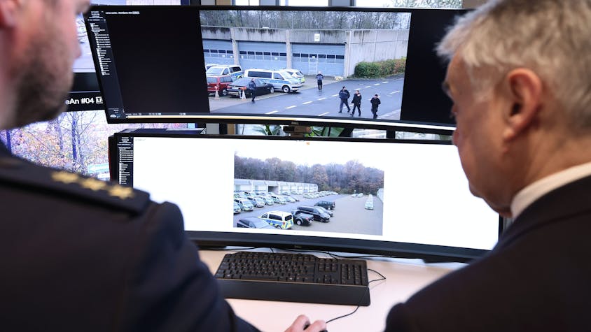 Christoph Meurers (l) erklärt Herbert Reul (CDU), Innenminister von NRW, die Aufnahmen der neuen mobilen Videobeobachtungsanlage der Polizei.&nbsp;