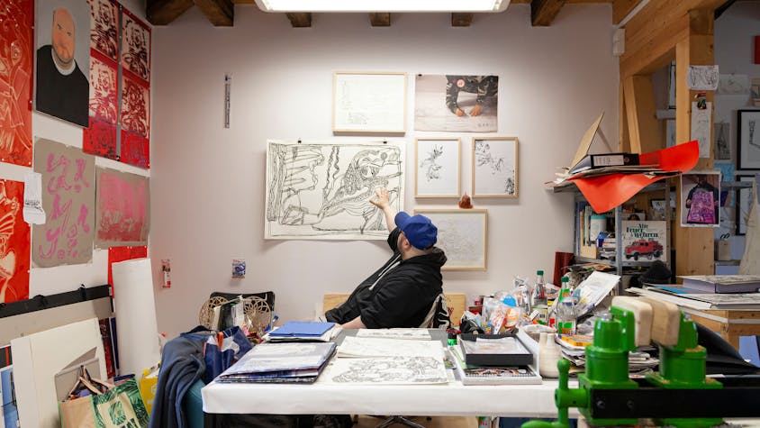 Künstler Markus Schmitz sitzt inmitten seiner Scherenschnitt-Werke im Atelier Goldstein.