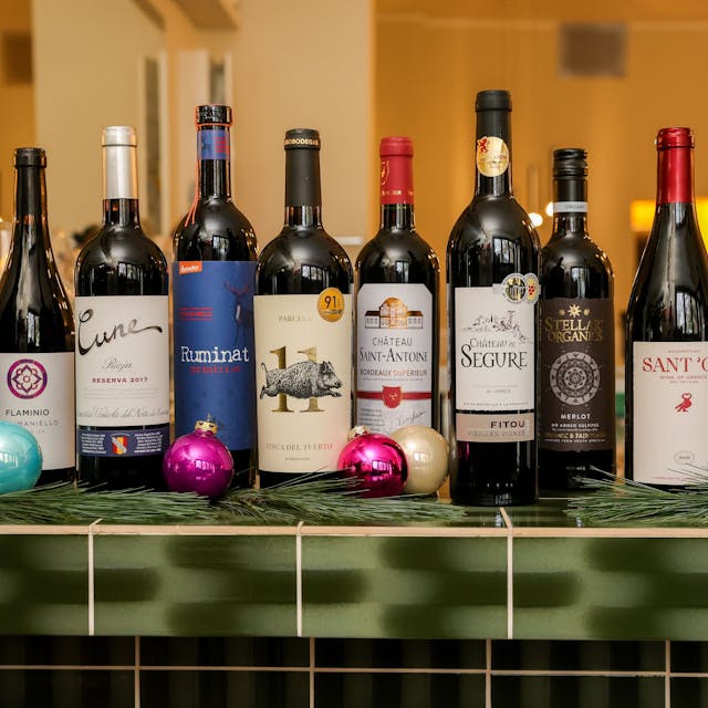 Zehn Flaschen Rotwein stehen auf einem Thekentresen, weihnachtlich geschmückt.