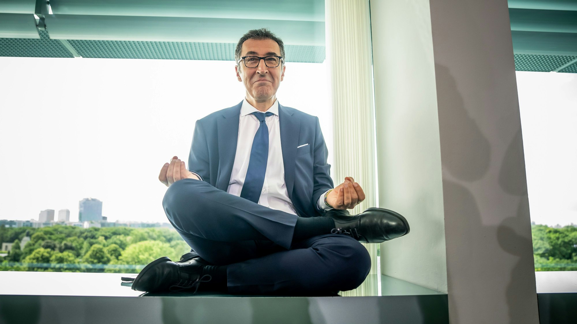 Cem Özdemir sitzt im Schneidersitz auf einer Fensterbank.