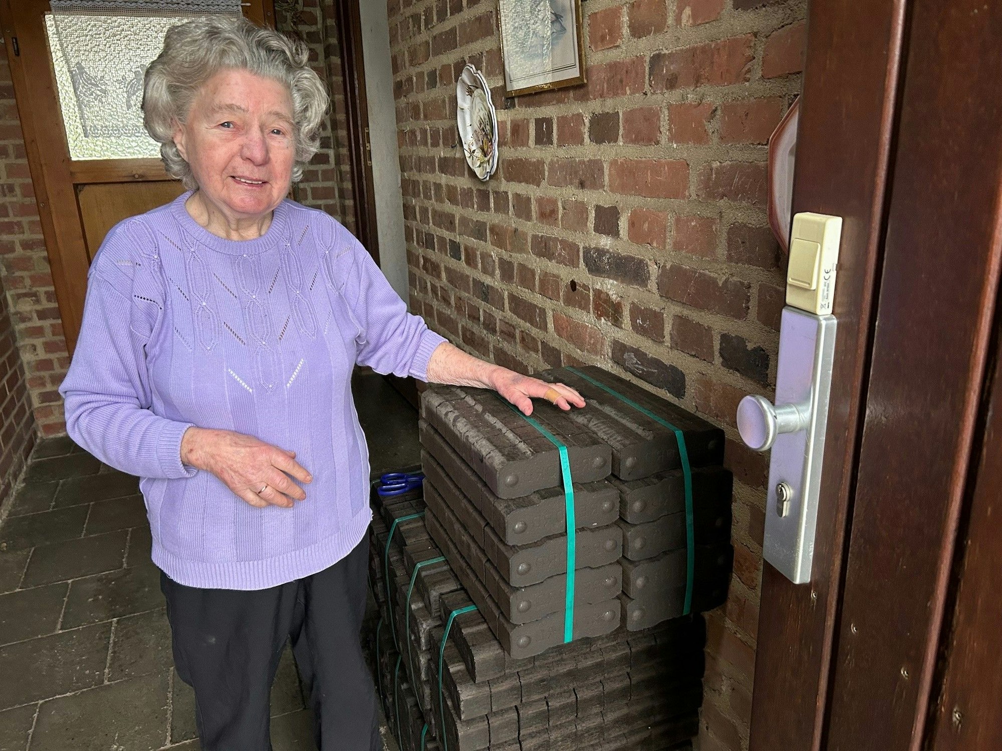 Anni Hartwig (91) in ihrem Haus in Morschenich im Rheinischen Braunkohlerevier. Sie lebt dort seit 50 Jahren. Sie steht neben einem Stapel Kohlebriketts in ihrem Haus im Vorflur.