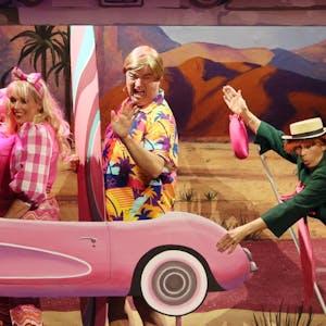 Anna Rixmann, Tom Simon und Martina Klinke als Hänneschen-Figuren in Barbie-Version mit einem pinkfarbenen Papp-Auto.