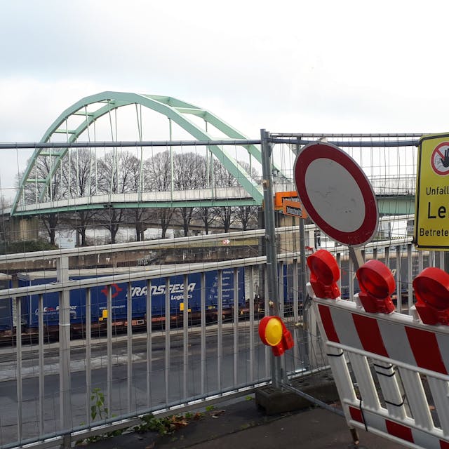 Eine Absperrung an einer Brücke mit vielen Schildern und rot-weißer Bake ist zu sehen.