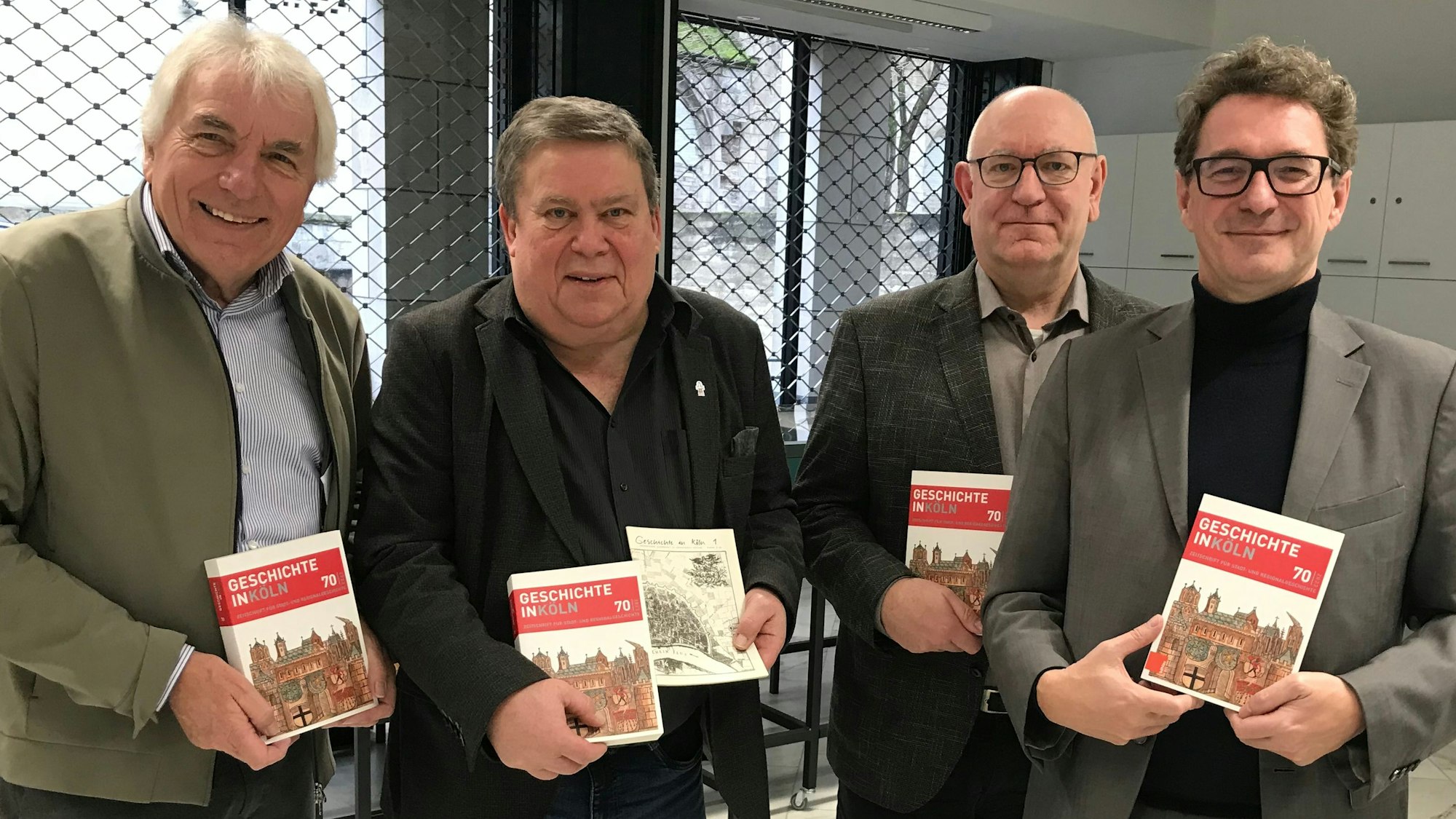Zu sehen sind vier Männer, in den Händen halten sie die Zeitschrift „Geschichte in Köln“.