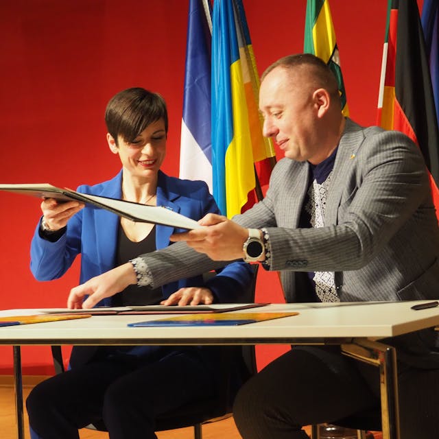 Carolin Weitzel und Igotr Hirchak unterzeichnen ein Dokument.