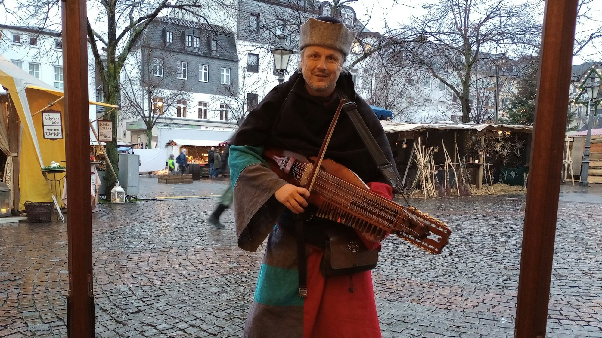 Ein Mann in mittelalterlicher Tracht spielt auf einem Instrument.
