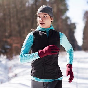 Eine junge Frau joggt durch einen verschneiten Wald
