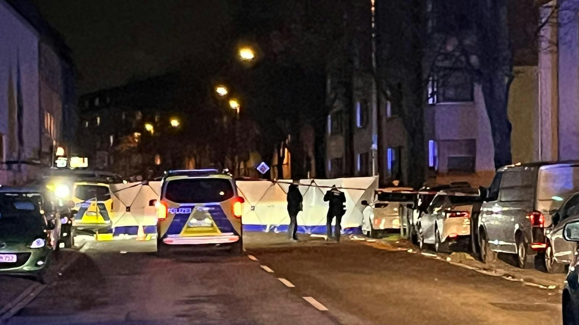 Mehrere Polizei-Autos an einem Tatort in Köln, der Bereich ist abgesperrt.