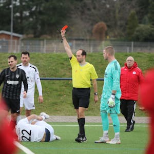 Der Schiedsrichter zeigt Lein Reimer die Rote Karte. Vor ihm auf dem Boden liegt Marco Weinhold, der sich das rechte Bein festhält.