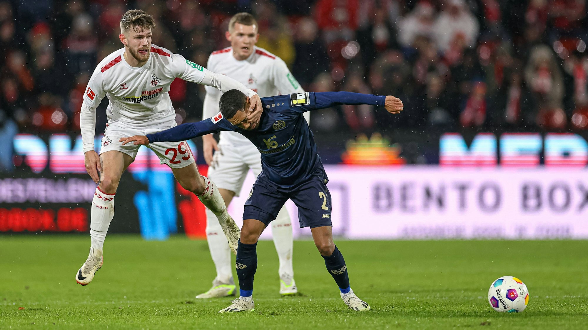 Jan Thielmann greift im Spiel des 1. FC Köln gegen Mainz 05 ins Gesicht von Gegenspieler Phillip Mwene.