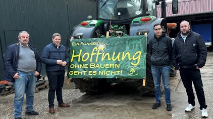 Das Foto zeigt die Landwirte und Landrat Markus Ramers neben einem Traktor, an dem ein Plakat mit der Aufschrift „Ein Funken Hoffnung. Ohne Bauern geht es nicht“ befestigt ist.